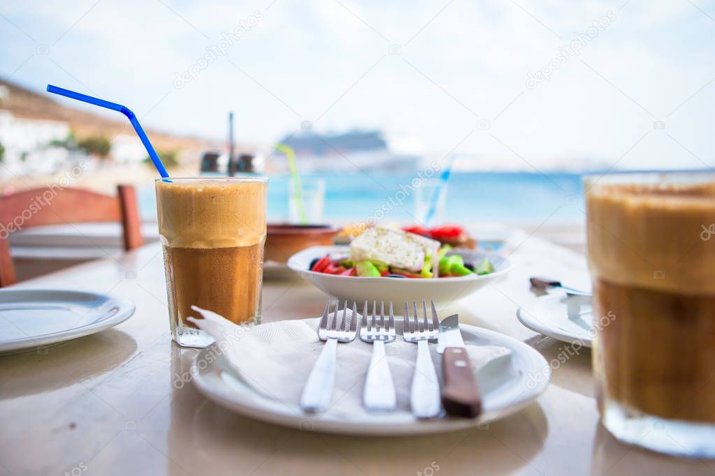 Traditional lunch with delicious fresh greek salad, frappe and brusketa served for lunch at outdoor cafe