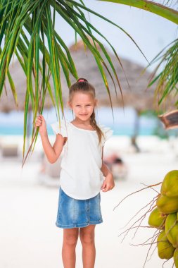 Beyaz tropikal sahilde hindistan cevizi yakınında küçük sevimli bir kız.