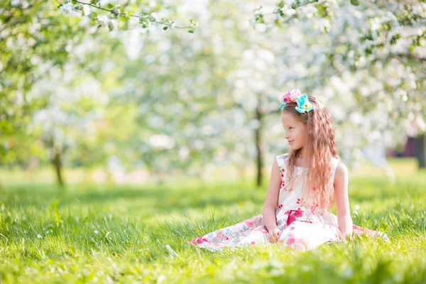 Söt liten flicka i blommande äppelträd trädgård på våren dag — Stockfoto