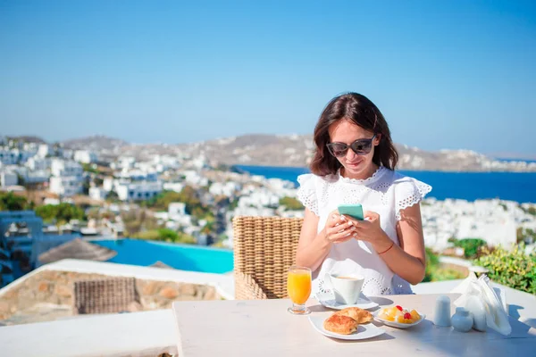 Ung kvinna med smartphone i utomhus café. Glad tjej njuta av morgonen tid i café med vacker utsikt — Stockfoto