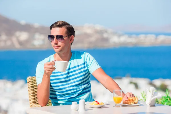 Turista desayunando con café en la cafetería al aire libre con una vista increíble de la ciudad de Mykonos . — Foto de Stock