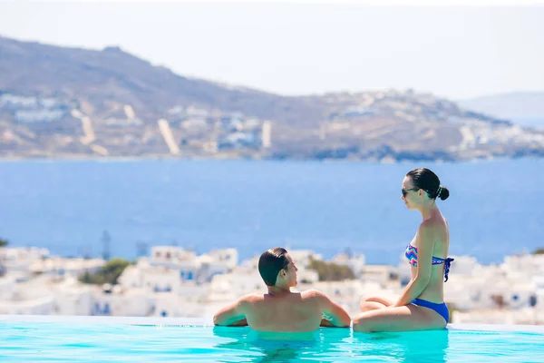 Happy young romantic couple relaxing on the edge of swimming pool — Stock Photo, Image