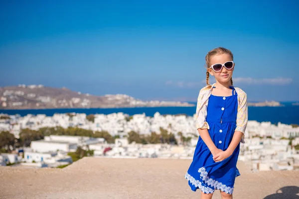Kleines Mädchen in blauem Kleid im Freien. Kind in der Straße eines typisch griechischen traditionellen Dorfes auf der Insel Mykonos, in Griechenland — Stockfoto