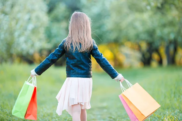 Adorable petite fille avec des sacs à provisions à l'extérieur — Photo