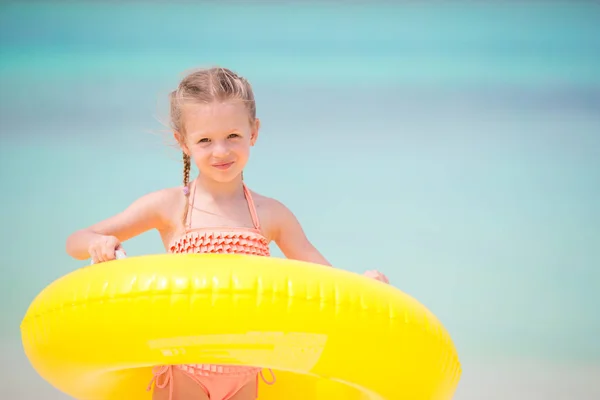 Menina pequena com círculo de borracha inflável amarelo que vai nadar no oceano — Fotografia de Stock