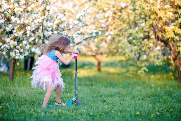 Little girl having fun in blooming apple tree garden on spring day — Stock Photo, Image