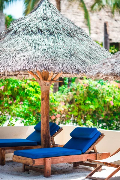 Sunbeds and umbrella at beautiful tropical resort outdoors — Stock Photo, Image