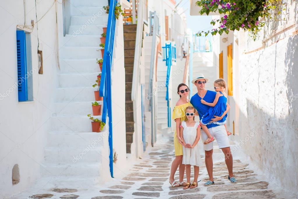 Family vacation in small old greek town. Parents and kids at street of greek traditional village on Mykonos Island