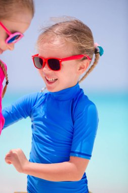 Mutlu kız beyaz plajda küçük kız kardeşi ile eğleniyor