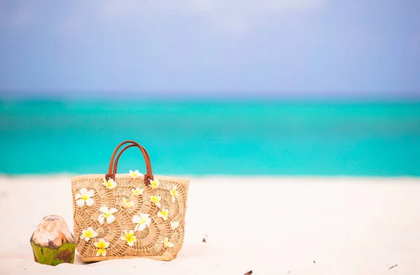 Strandtas met frangipani bloemen en kokosnoot op witte strand. Closeup strand accessoires. — Stockfoto