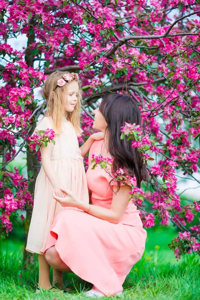 Madre e hija en el jardín floreciente disfrutar del día cálido — Foto de Stock