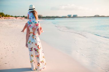 Tropik plajda küçük sevimli bir kız ve genç bir anne.