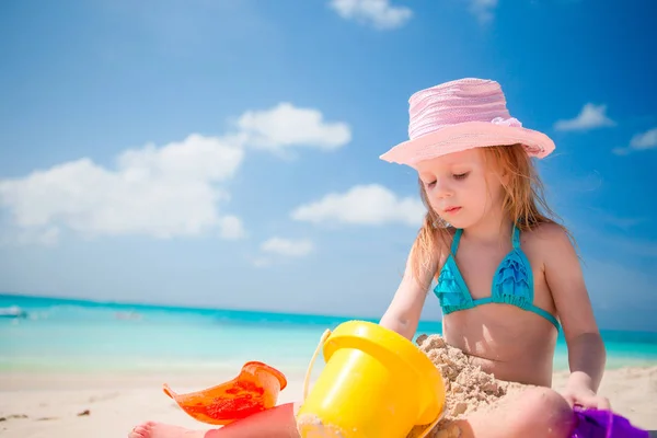 Malá holčička v tropické dovolené hraje s hračkami, pláž — Stock fotografie