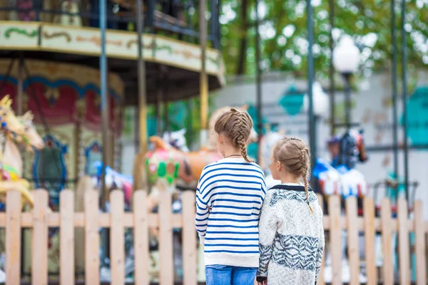 Adorable little girls near the carousel outdoors — Stock Photo, Image