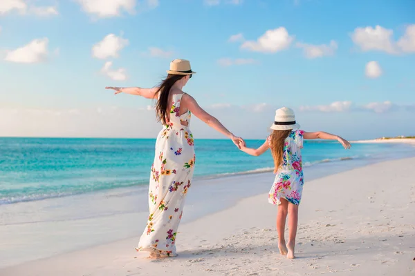 Klein schattig meisje en jonge moeder op tropisch strand — Stockfoto