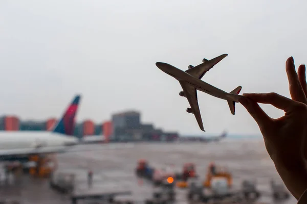 Closeup hand met een model van het vliegtuig op de luchthaven — Stockfoto