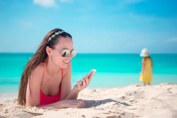 Jonge vrouw met mobiele telefoon op het strand — Stockfoto
