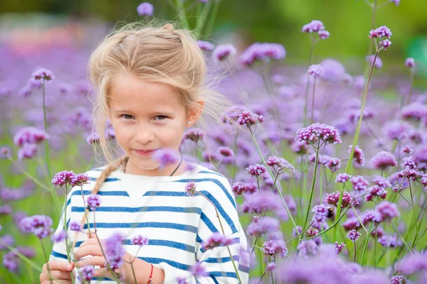 Niña adorable oliendo flores coloridas al aire libre —  Fotos de Stock