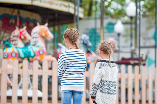 Adorable little girls near the carousel outdoors — Stock Photo, Image