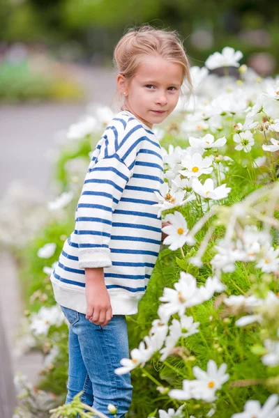 Kleines entzückendes Mädchen, das bunte Blumen im Freien riecht — Stockfoto