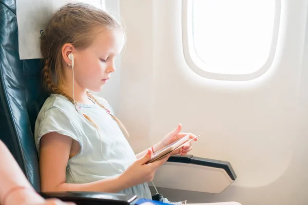 Entzückendes kleines Mädchen, das mit dem Flugzeug reist. Nettes Kind mit Laptop in Flugzeugfenster — Stockfoto