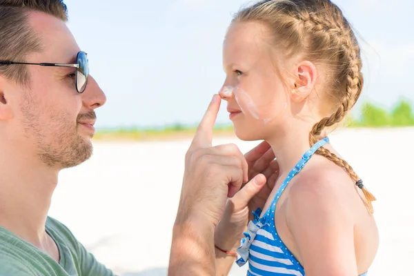 Родитель наносит солнцезащитный крем на детский нос. Портрет милой девушки в креме для загара — стоковое фото