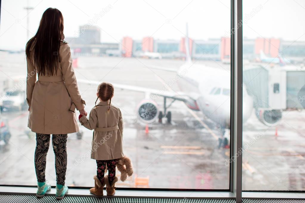 Mother and little girl in airport waiting for boarding