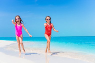 Küçük kızlar tropikal plaj birlikte sığ su oynarken eğleniyor