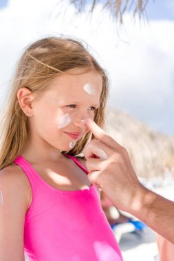 Babası kızı burun için güneş krem uygulamak. Suncream şirin kız portresi