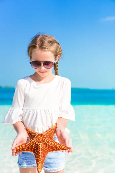 Adorable petite fille avec étoile de mer sur la plage blanche vide — Photo