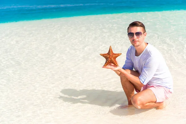 Glad ung kille med sjöstjärnor på vita stranden i i naturreservat — Stockfoto