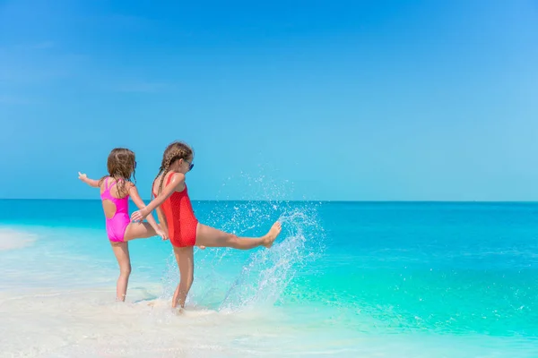 Niñas divirtiéndose en la playa tropical jugando juntas en aguas poco profundas —  Fotos de Stock