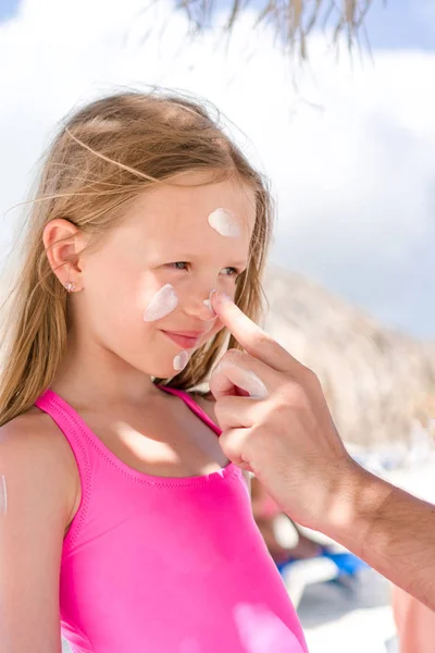 Padre aplicando crema solar a la nariz de la hija. Retrato de linda chica en crema solar — Foto de Stock