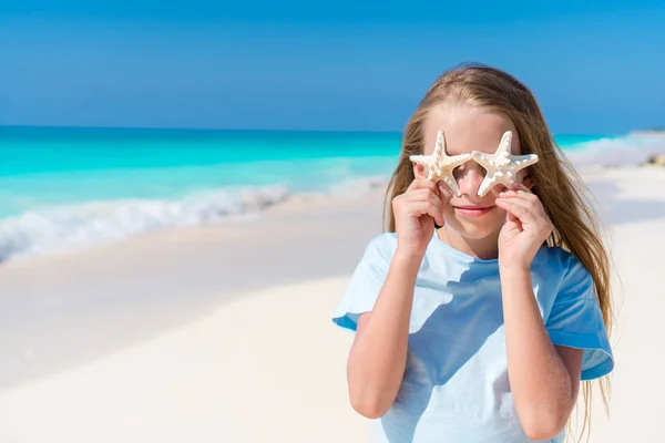 Adorável menina com estrela do mar na praia branca vazia — Fotografia de Stock