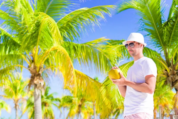 Ung man dricka kokosmjölk varm dag på stranden — Stockfoto