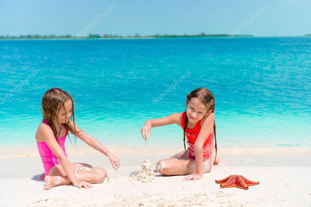 Little girls having fun at tropical beach playing together at shallow water