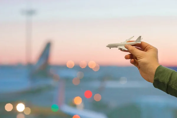 Closeup hand met een vliegtuig model speelgoed op luchthaven achtergrond groot venster — Stockfoto