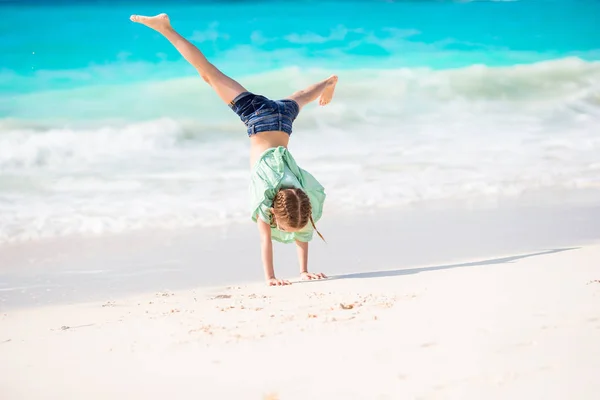 Bedårande liten flicka på stranden med en massa kul. Sportig aktiva barn att göra hjulet — Stockfoto