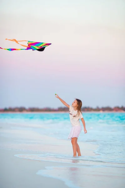 Tropik sahilde uçurtma uçan ile küçük kız. Çocuk oyun okyanus kıyısında. Çocuk plaj oyuncakları ile. — Stok fotoğraf