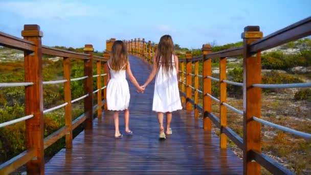 Kicsi gyerekek, egy fából készült hídon egy fehér strand és a türkizkék óceán felé — Stock videók