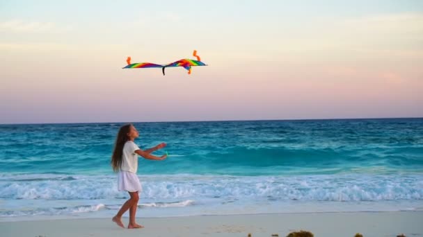Очаровательная маленькая девочка с летающим воздушным змеем на тропическом пляже. Счастливый ребенок играет на берегу океана с пляжным змеем. Медленный мойон — стоковое видео