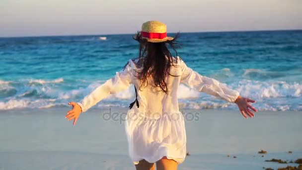 Baksidan på vacker kvinna på tropiska stranden i solnedgången njuter av havsutsikten. Glad tjej i klänning i slow motion — Stockvideo