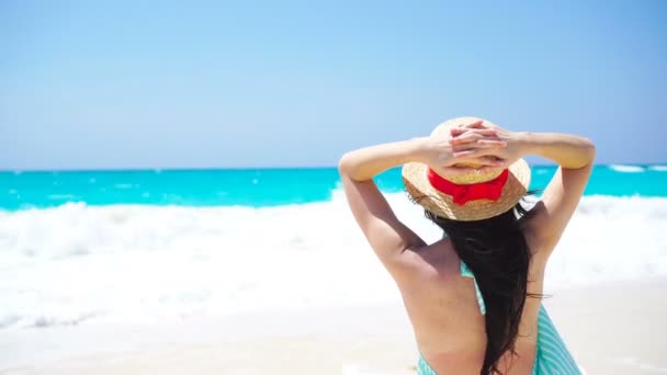 Zadní pohled krásné ženy v klobouku na letní dovolenou na bílé pláži. — Stock video