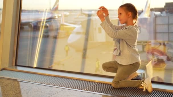 Очаровательная маленькая девочка играет с маленькой моделью самолета в аэропорту в ожидании посадки. Концепция полета и самолета . — стоковое видео