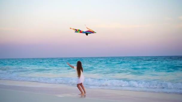 Adorable little girl with flying kite on tropical beach at sunset. Kids play on ocean shore. Child with beach toys. — Stock Video