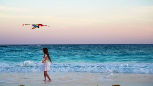 Schattig meisje met vliegende kite op tropisch strand. Kind spel aan Oceaan oever met prachtige zonsondergang. Slow motion. — Stockvideo