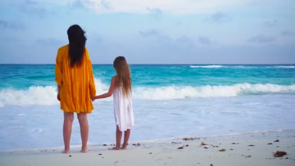 Klein schattig meisje en jonge moeder op tropisch strand in warme avond — Stockvideo