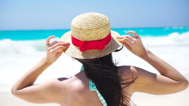 Вид сзади красивой женщины в шляпе на летний отдых на белом пляже . — стоковое видео
