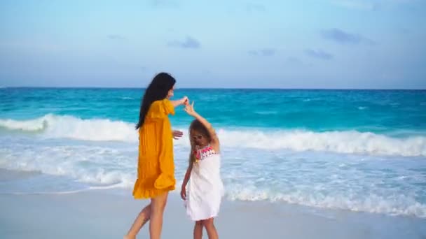 Liten bedårande flicka och ung mamma på tropical beach i varm kväll med vacker solnedgång — Stockvideo