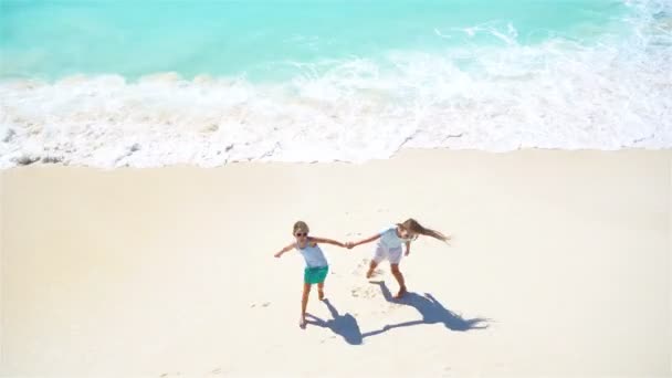 Adorabili bambini giocano insieme sulla spiaggia in acque poco profonde. Vista dall'alto di una spiaggia deserta con acqua turchese — Video Stock